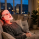 Relaxed woman wearing a red light therapy LED mask during an evening home session